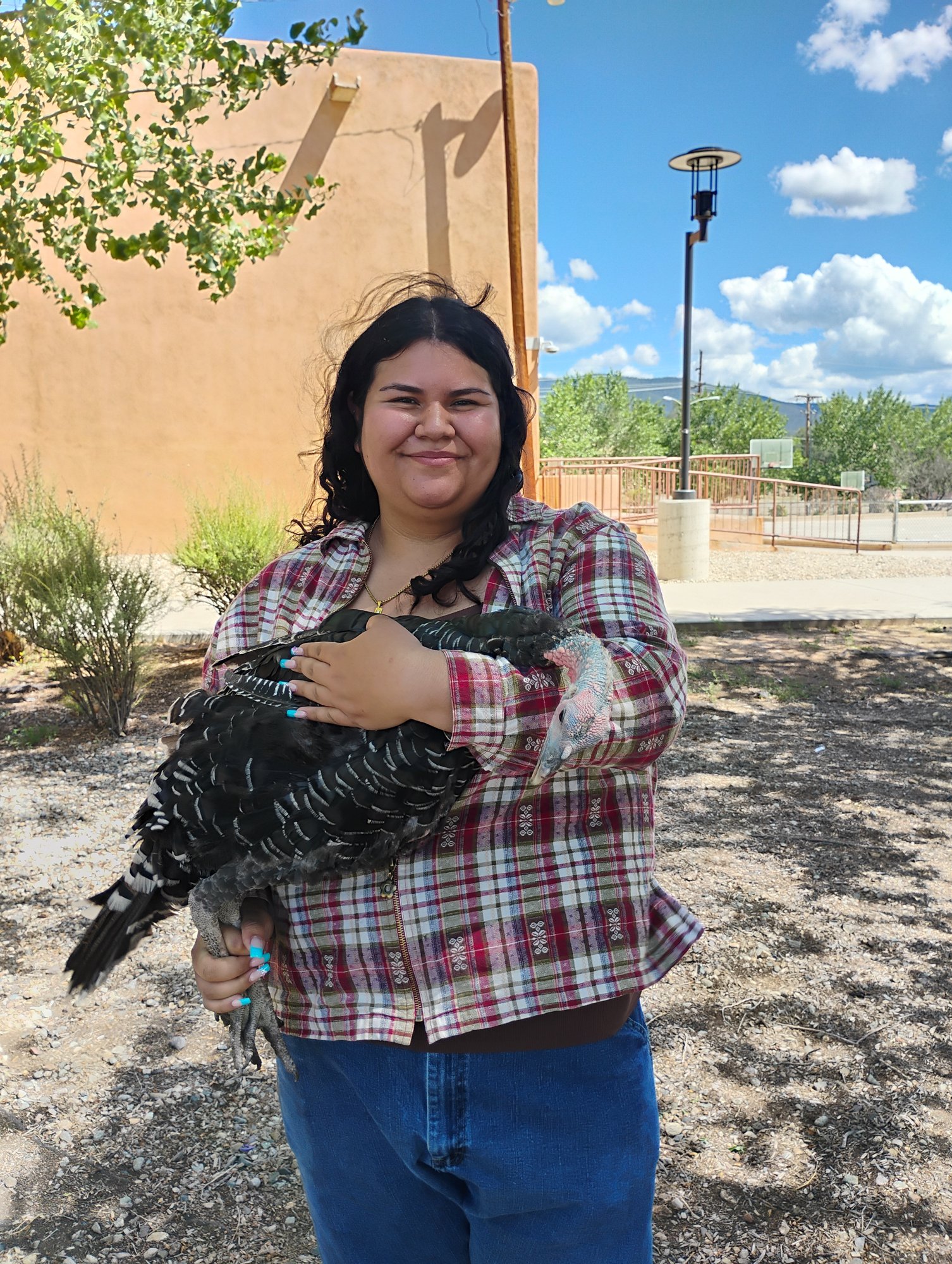 Andrea Montoya, Healthy Soils Intern, holding a turkey at Taos Land Trust